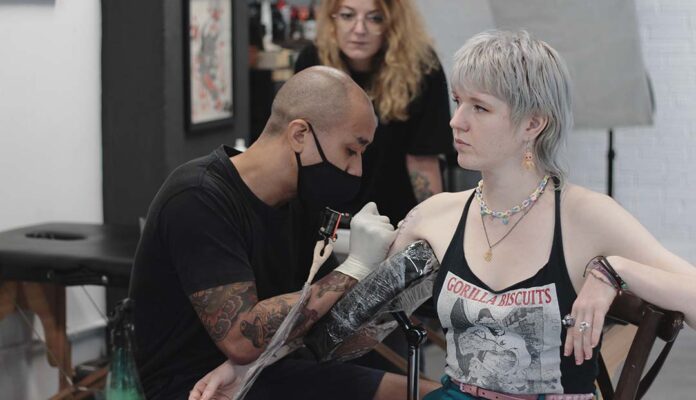 Tattoo artist applying a tattoo on a customer at The Hangout