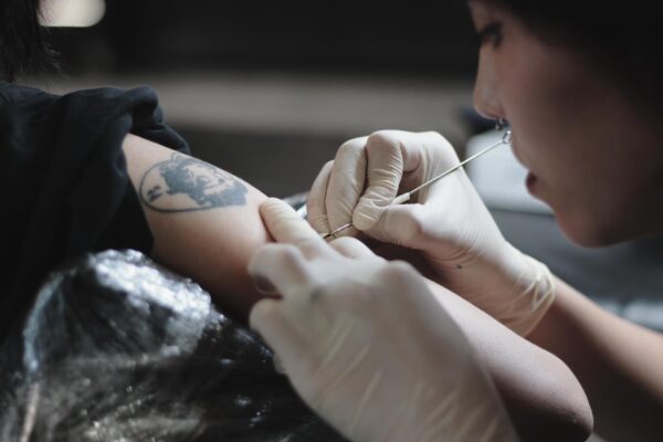 A female tattoo artist tattooing a customer at The Hangout Hoi An