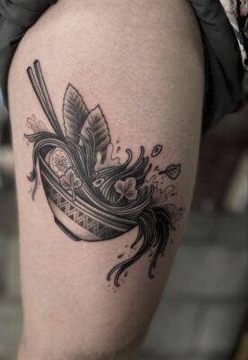 Thigh tattoo of a bowl of Vietnamese pho spilling out of the bowl in black ink