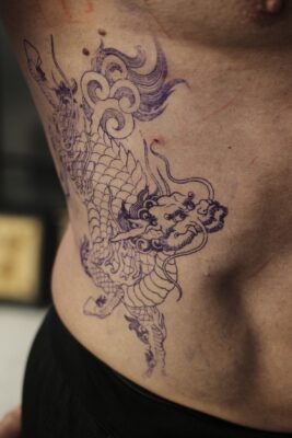 Rib tattoo outline of a dragon flying