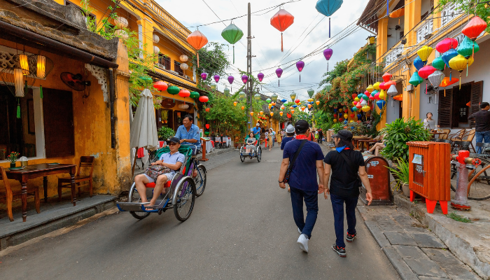 A photo of a couple walking past a cyclo in Hoi An Ancient Town