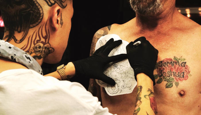 Tattoo artist applying a tattoo on a customer's chest