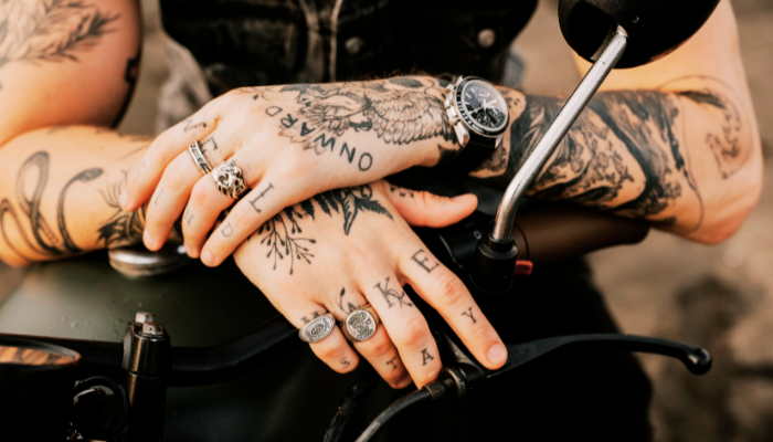 Close-up photo of someone with hand tattoos sitting on a motorcycle