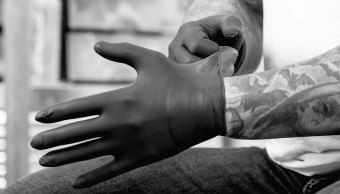 Close up black and white photo of a man wearing a latex glove